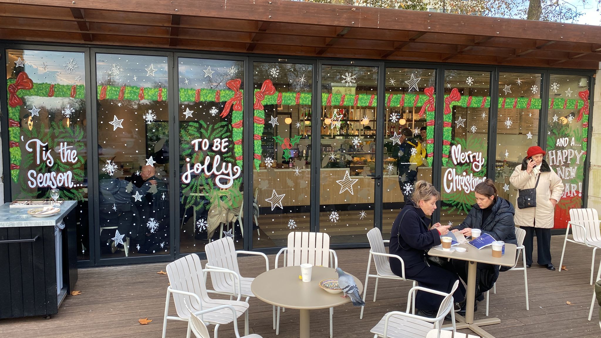 Christmas window painting with red bows, greenery and festive lettering
