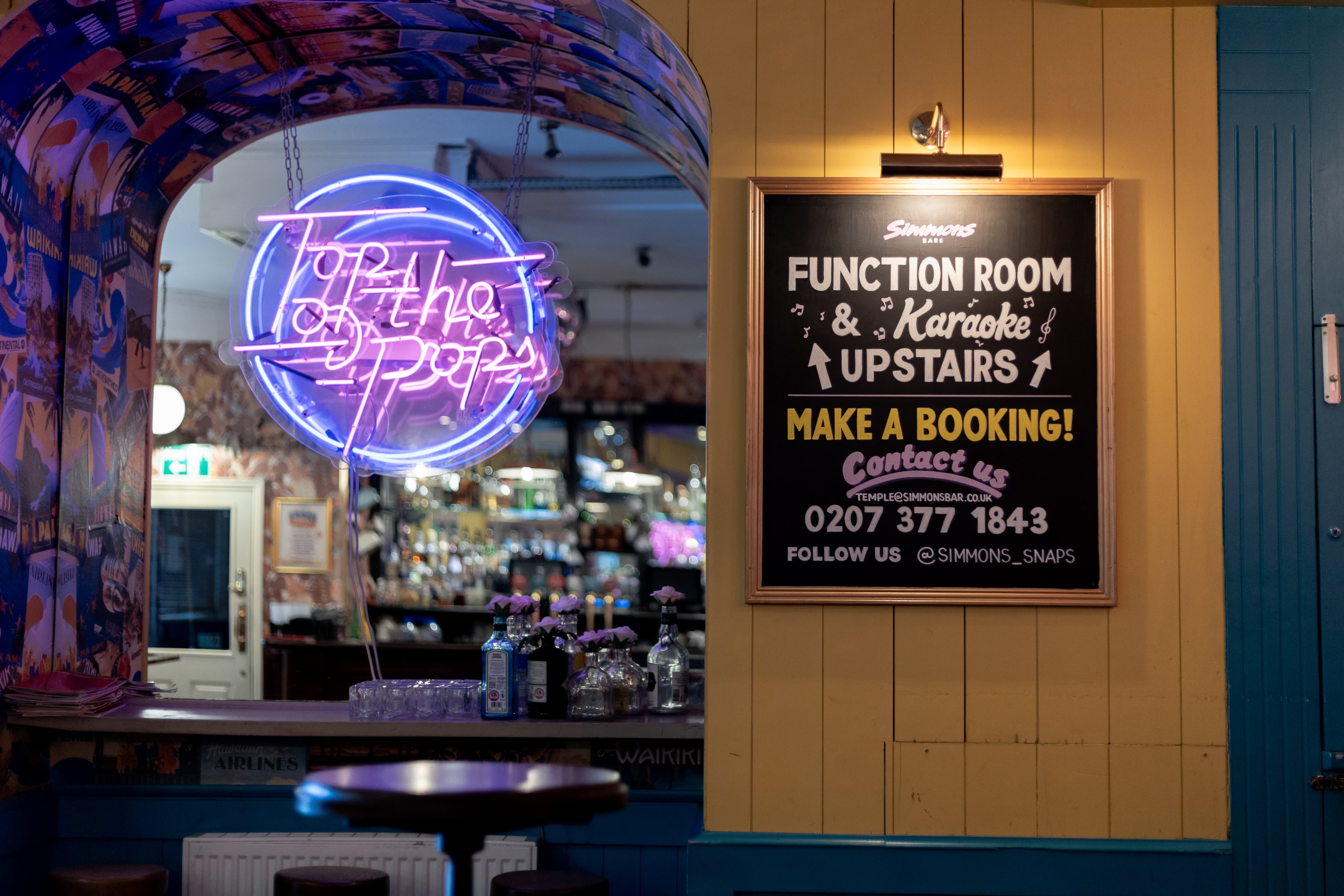 A hand-lettered Function Room and Karaoke blackboard beside a neon sign at Simmons.