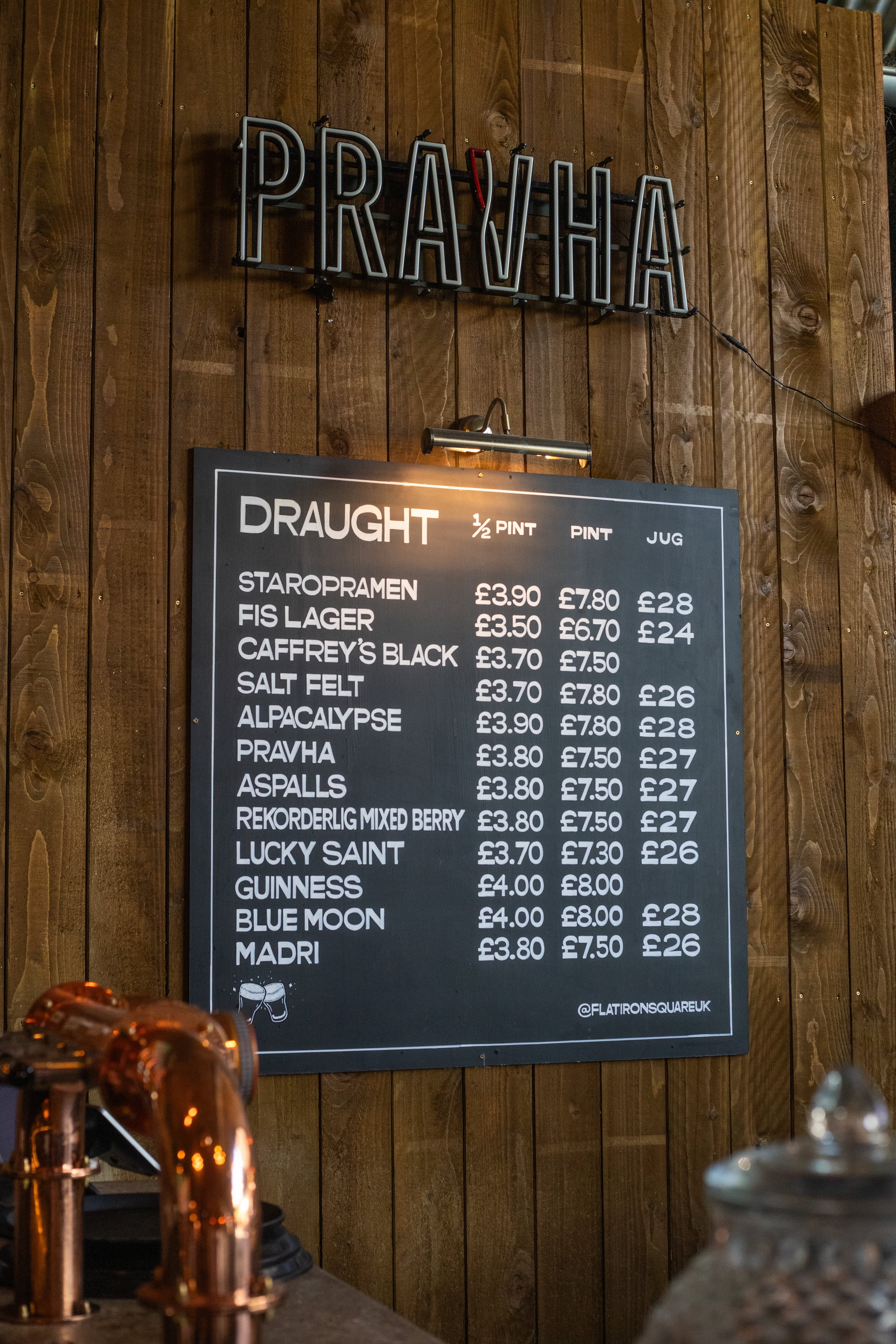 A hand-lettered draught beer menu beneath a Pravha sign.