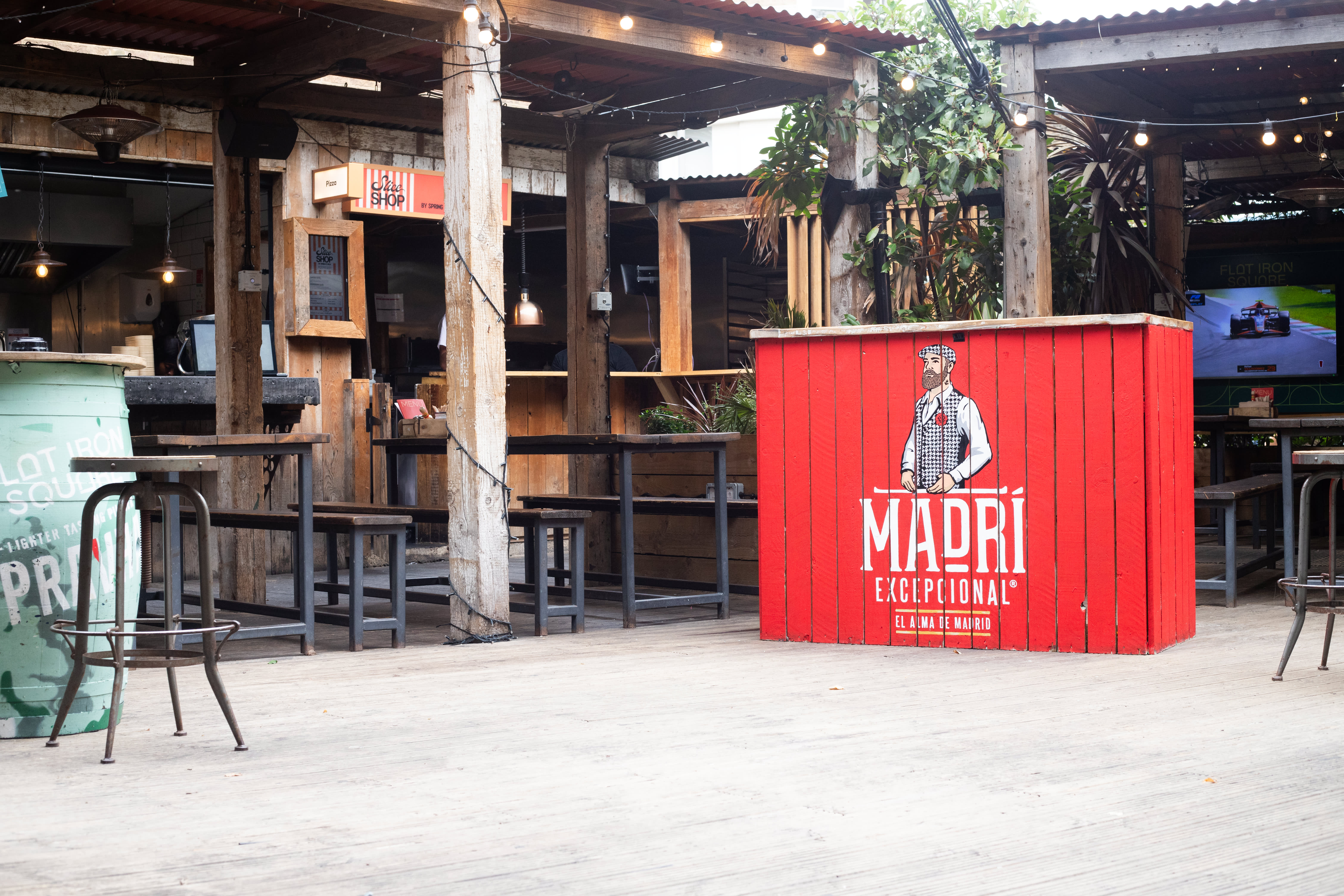 A red Madri-branded timber panel beside outdoor bar seating.