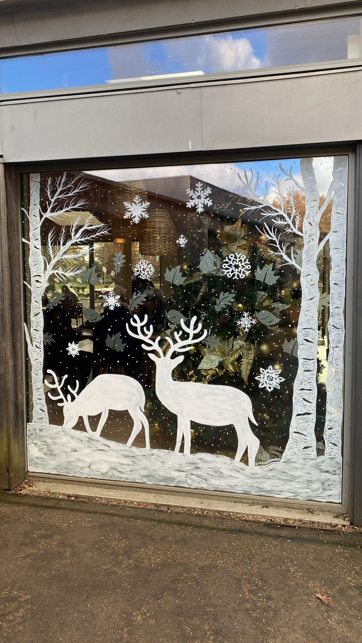 Winter woodland window painting with white deer, trees and snowflakes