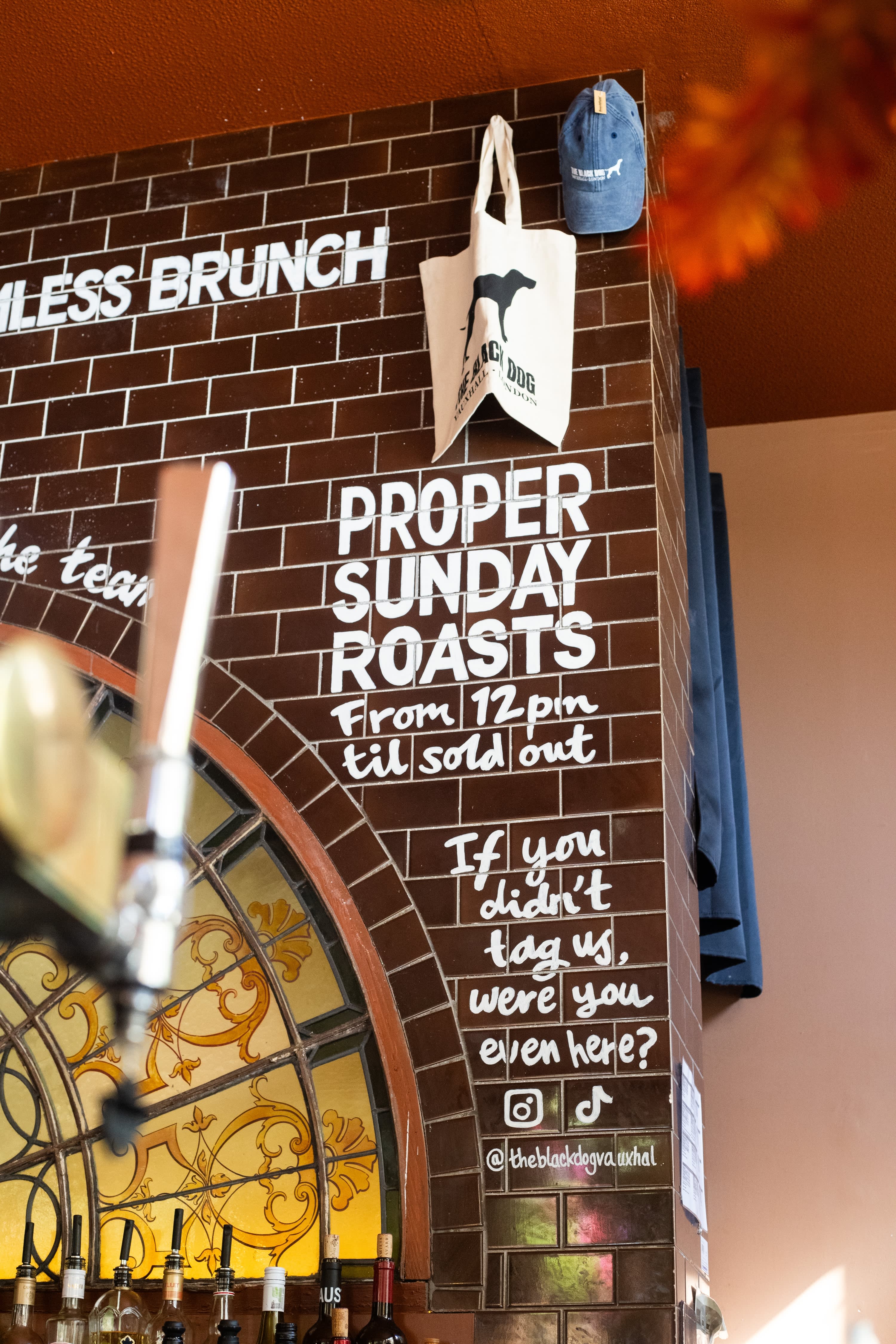 A hand-lettered Sunday roast menu beside a stained-glass window at The Black Dog.