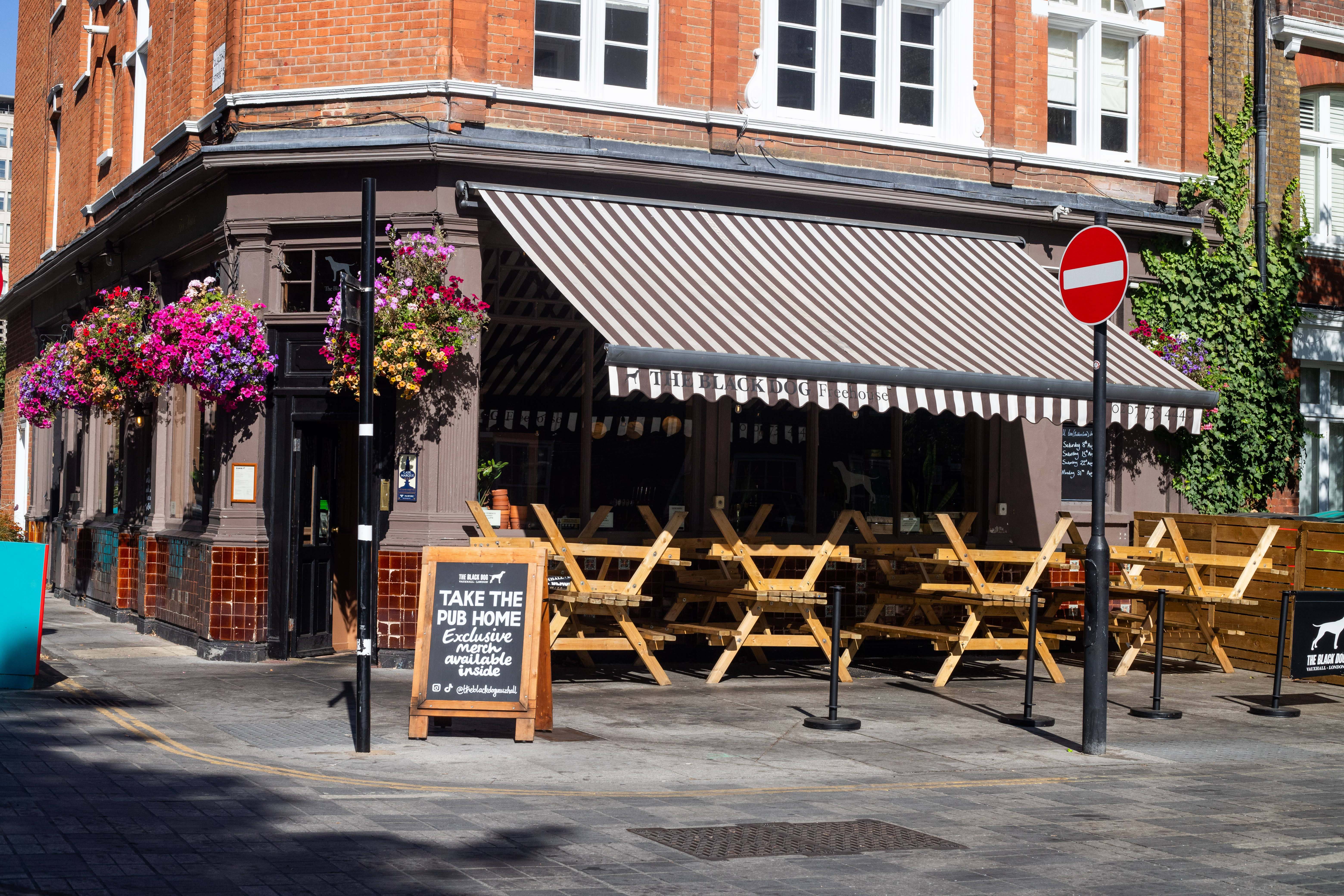 The Black Dog pub frontage with striped awnings, hanging flowers and outdoor seating.