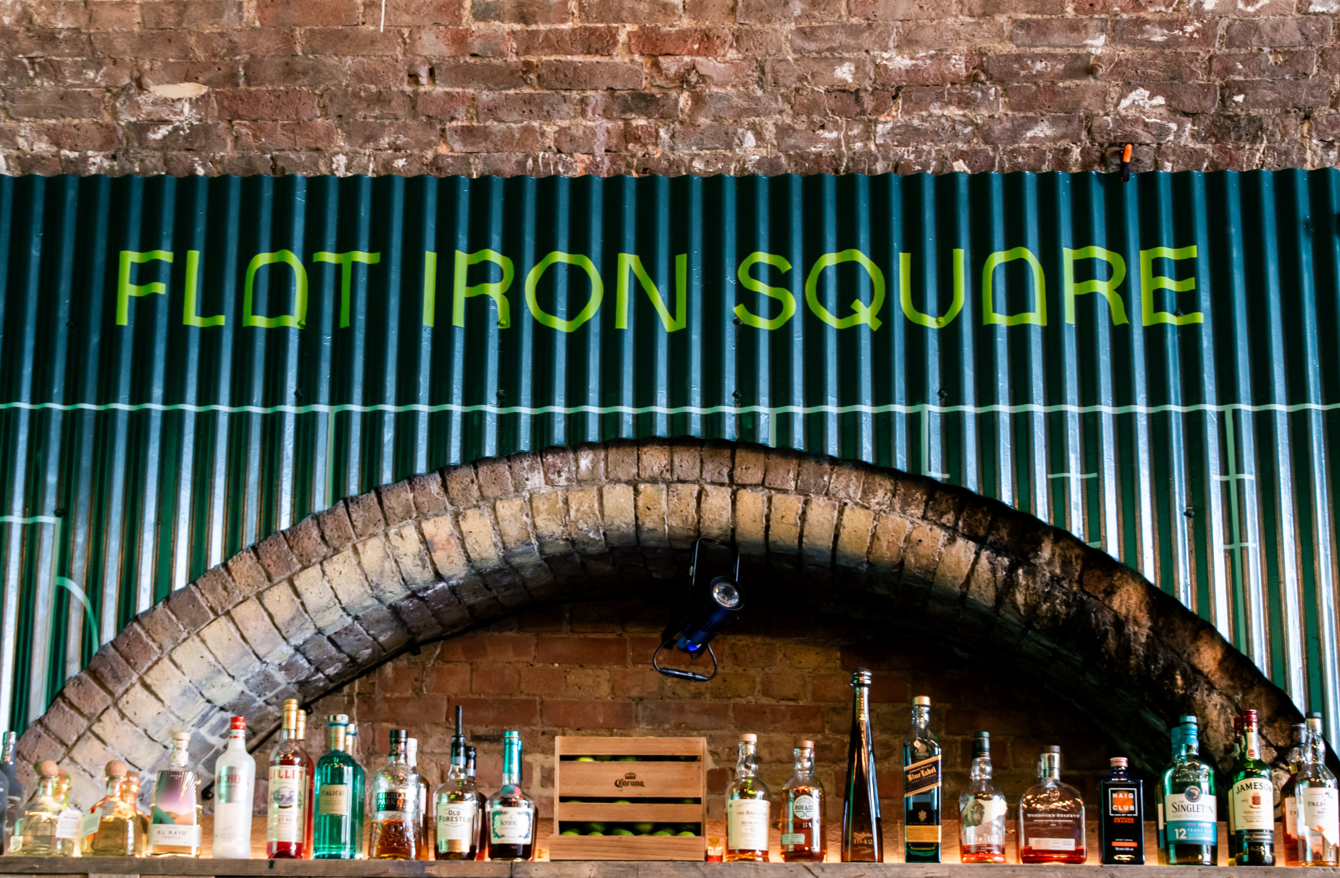 Flat Iron Square lettering above the brick archway and bar.
