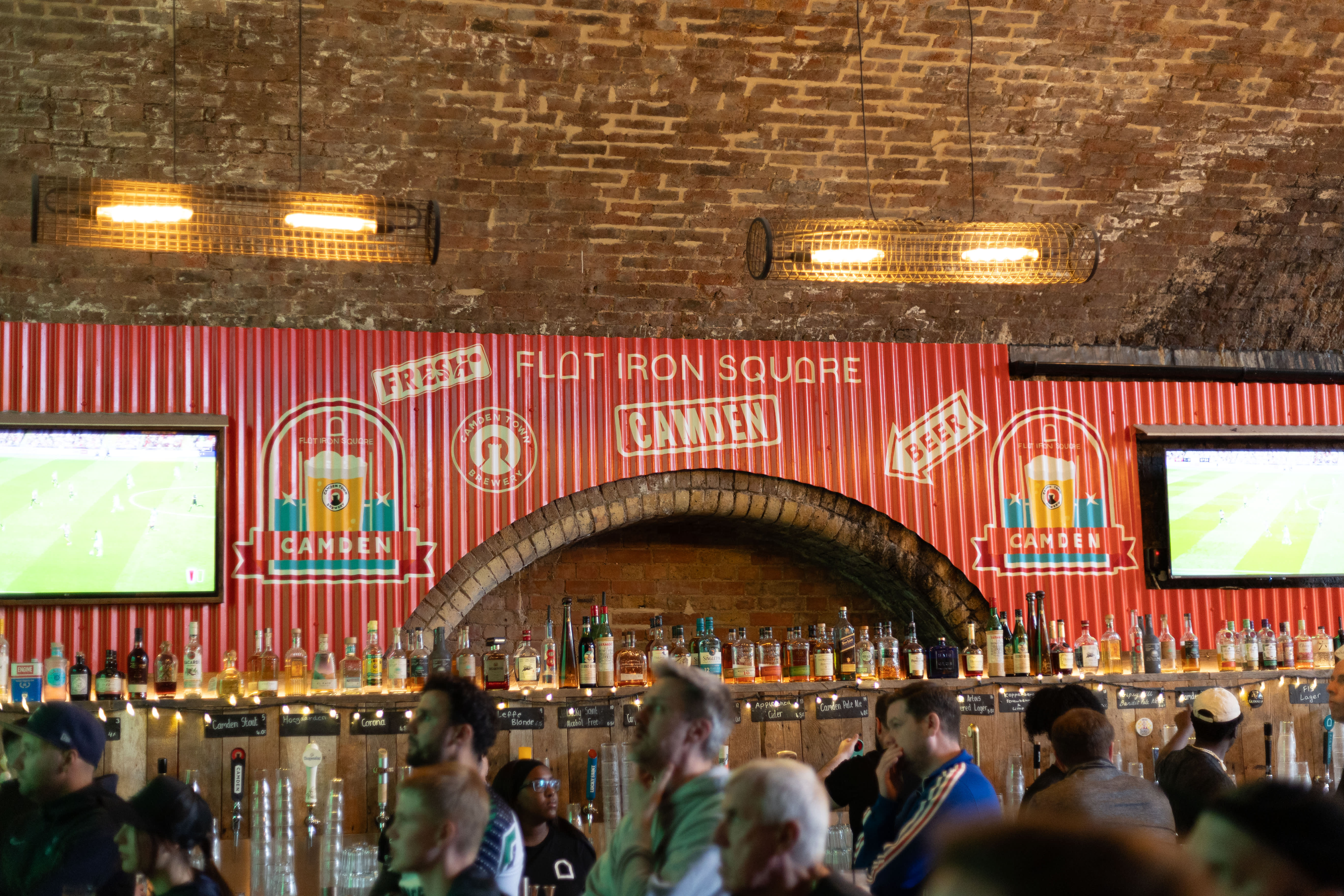 Hand-painted beer branding above a brick-arched bar at Flat Iron Square.