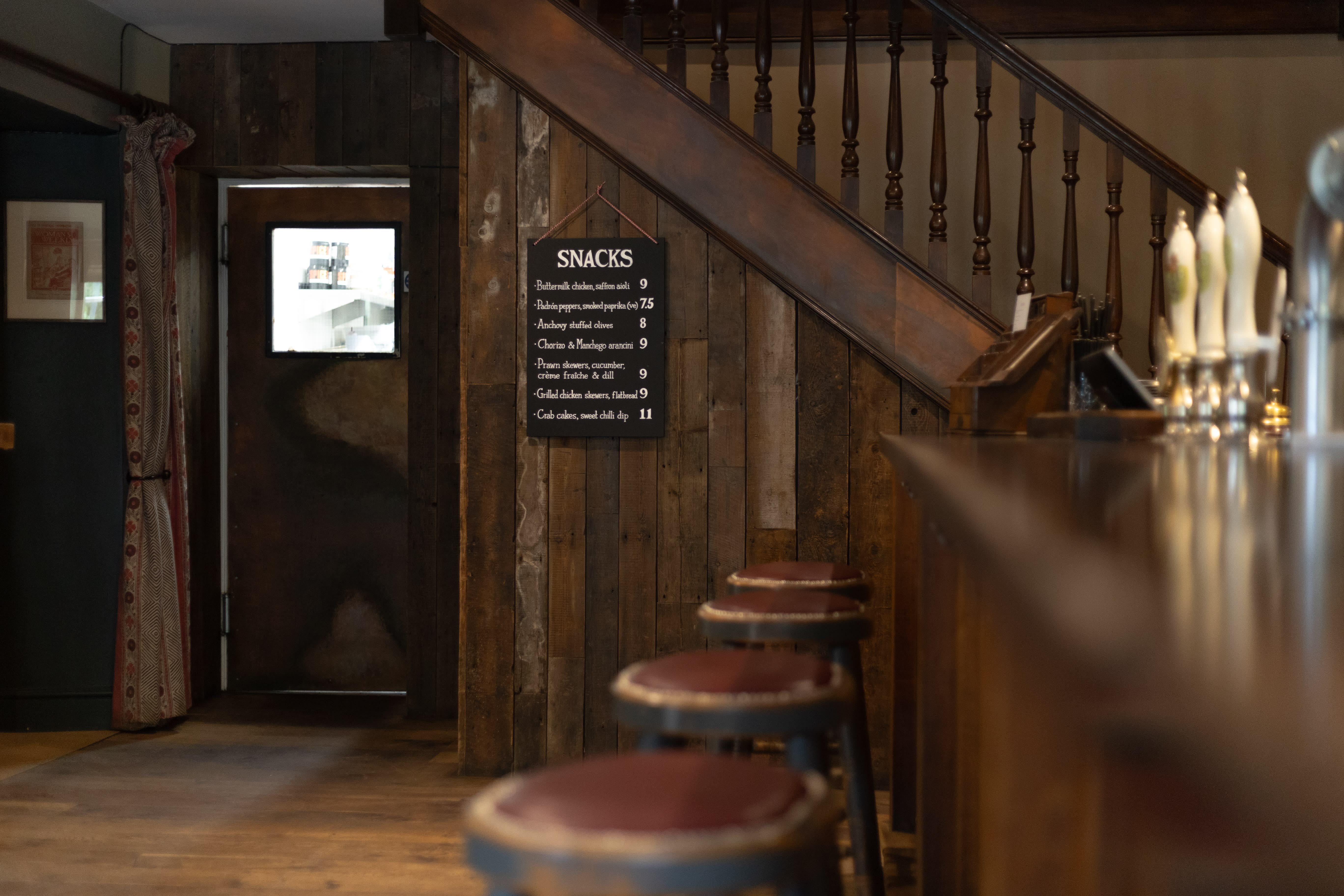 Hand-lettered snack menu beside the staircase inside a Lionhearth pub.