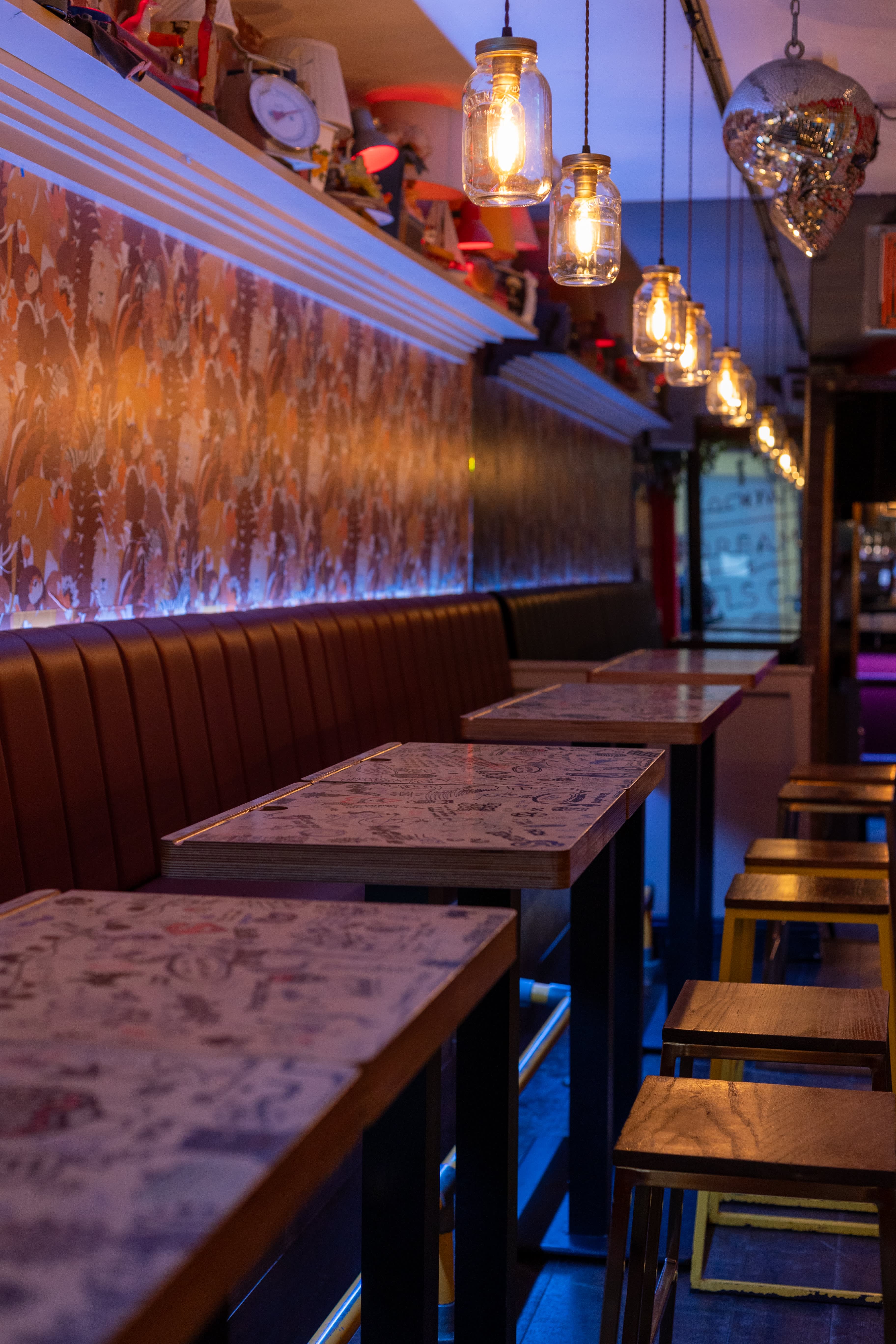 Booth seating and hand-illustrated tables beneath pendant lights at Simmons.