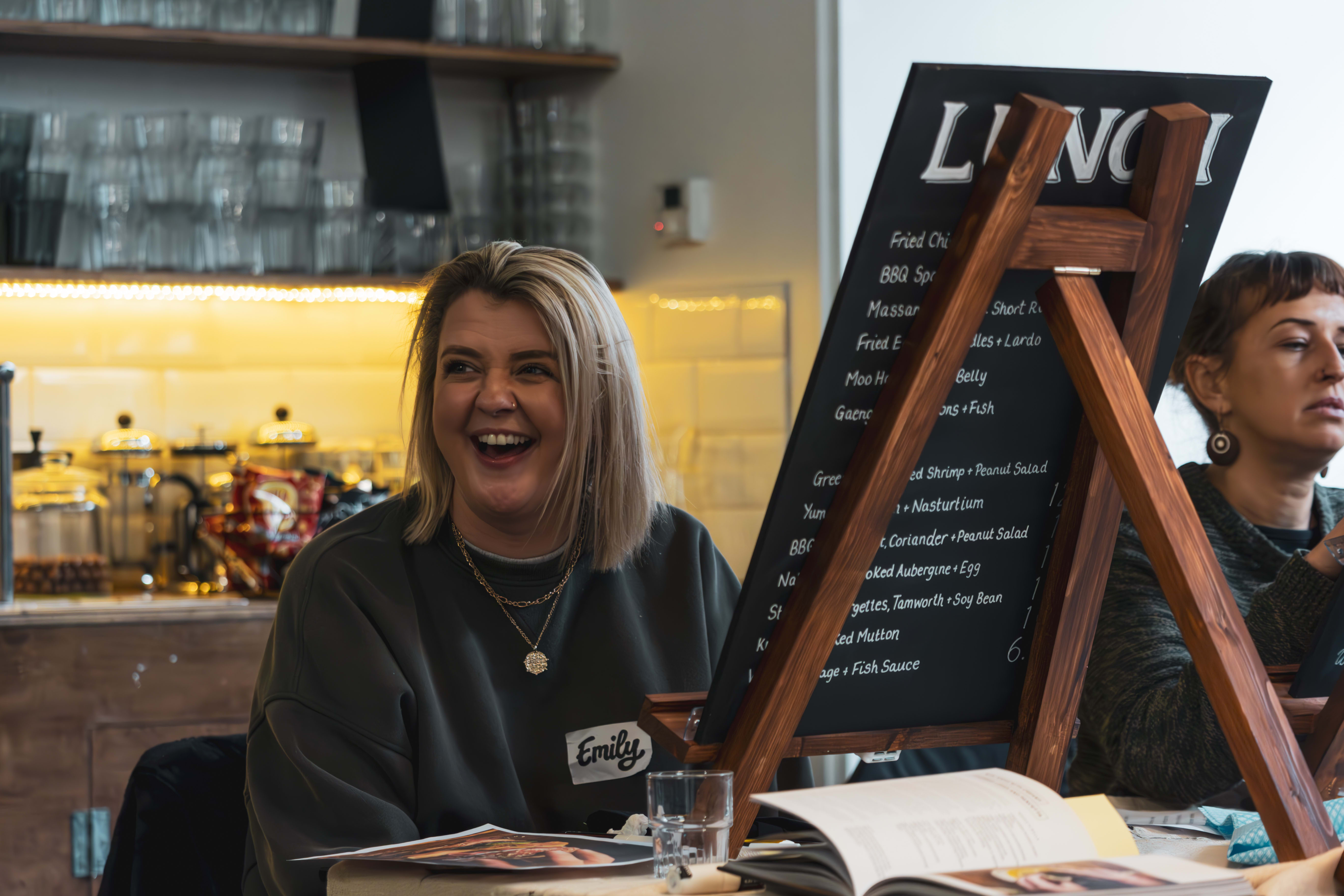 A smiling workshop participant sitting beside her blackboard on an easel.