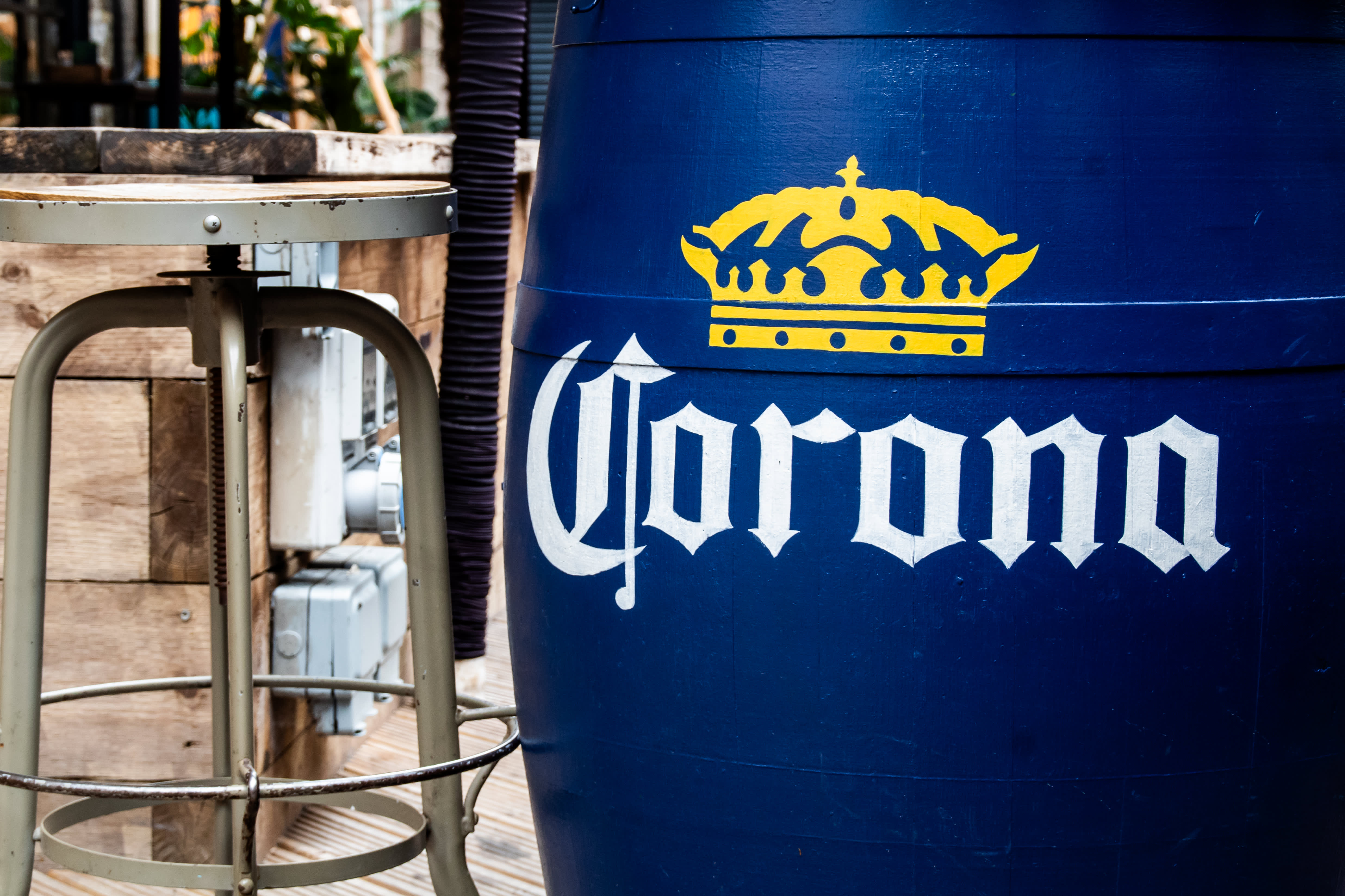 White and yellow Corona branding hand-painted on a blue barrel table.
