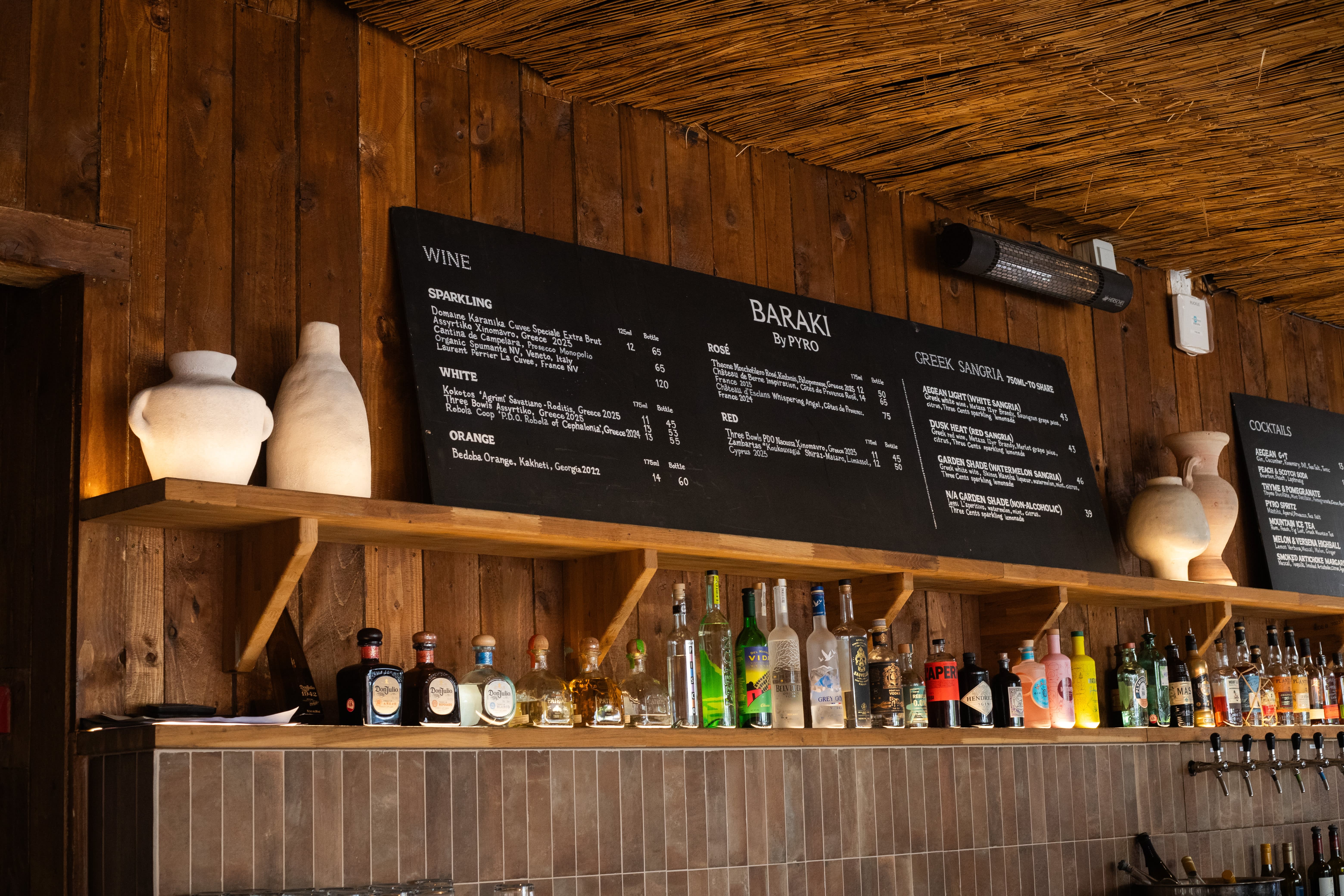 A row of blackboard wine and cocktail menus above a timber bar counter.