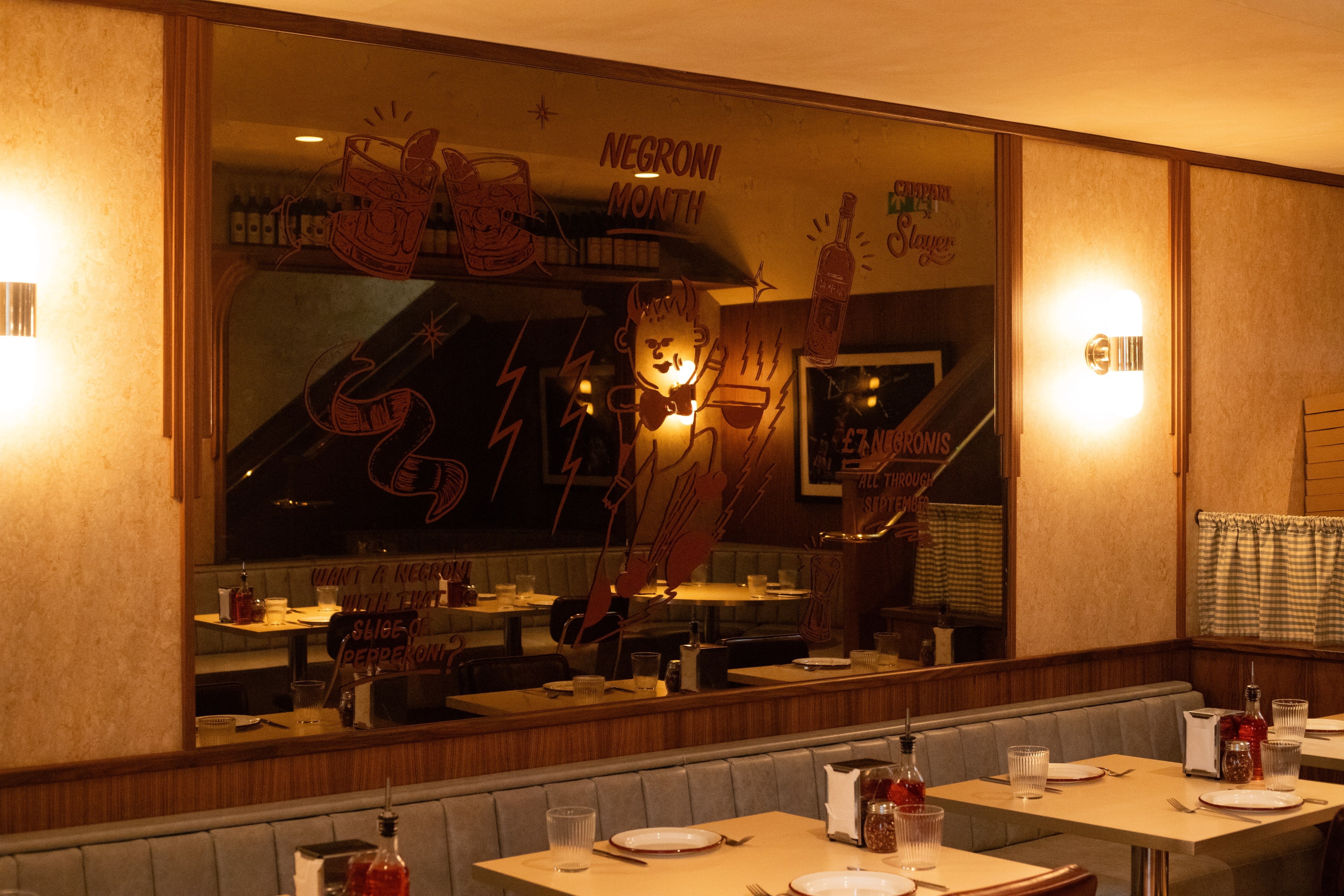A restaurant mirror decorated with hand-painted drinks lettering and playful illustrations.