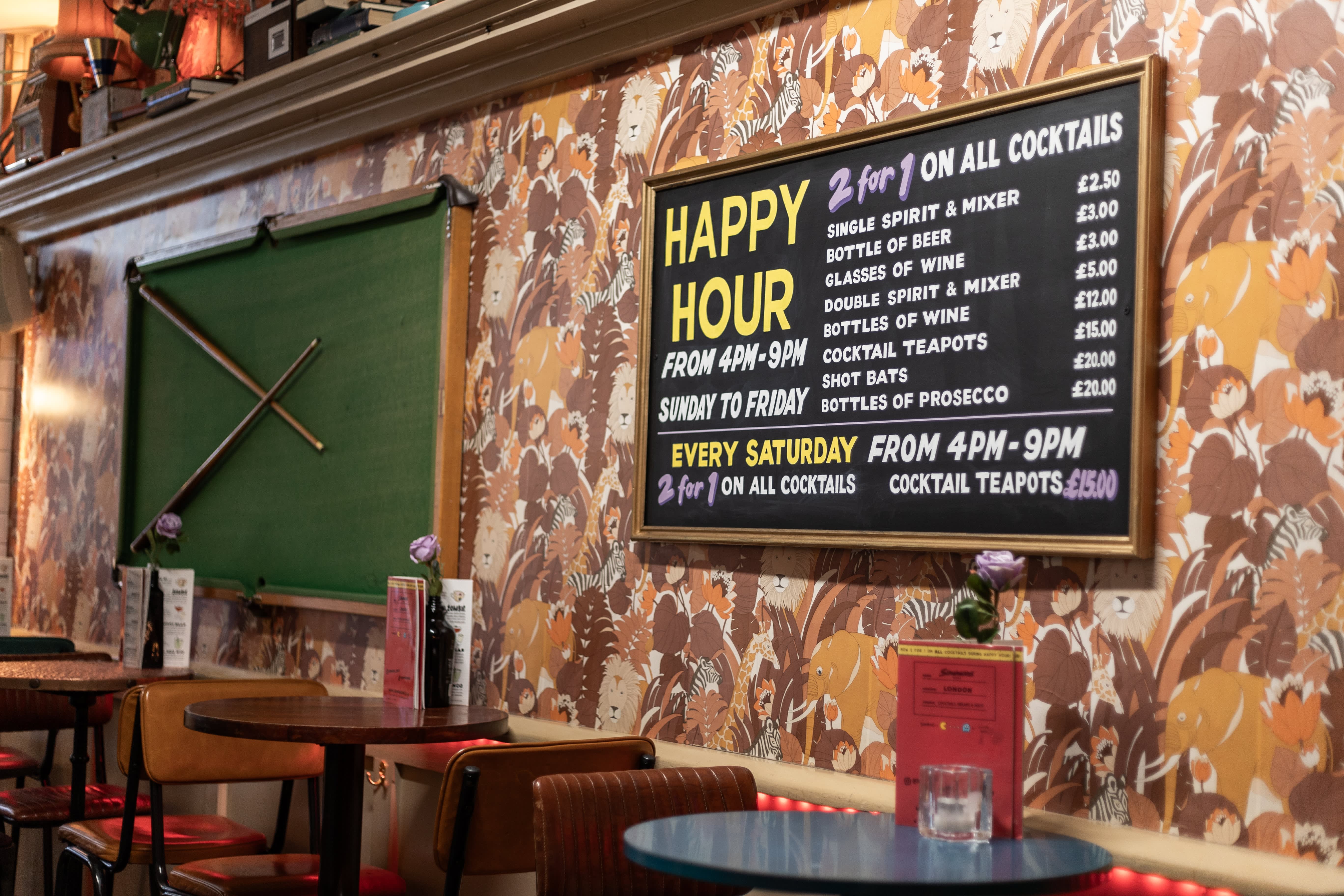 A hand-painted Happy Hour menu above booth seating at Simmons.