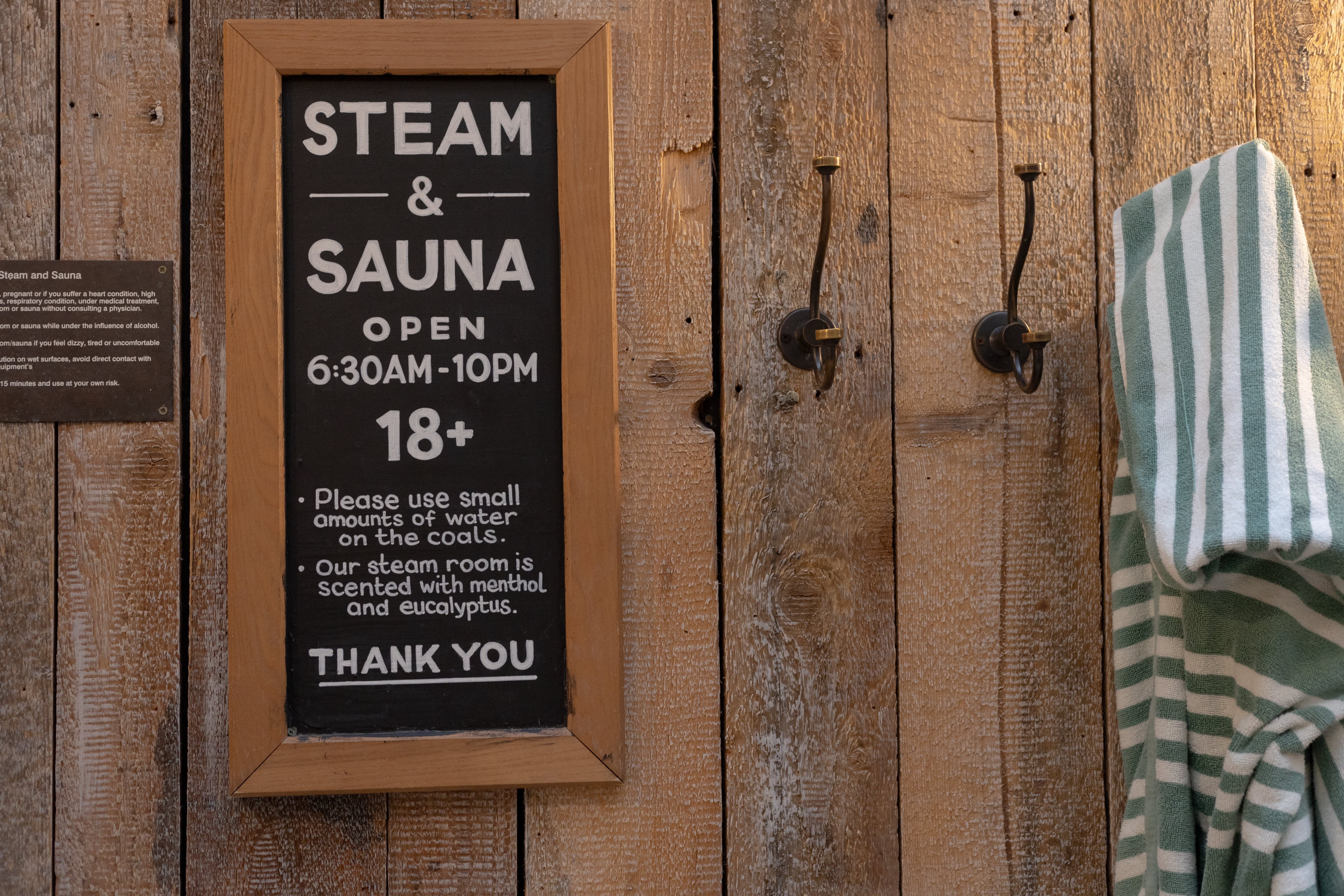 Hand-painted steam and sauna sign on a timber wall.