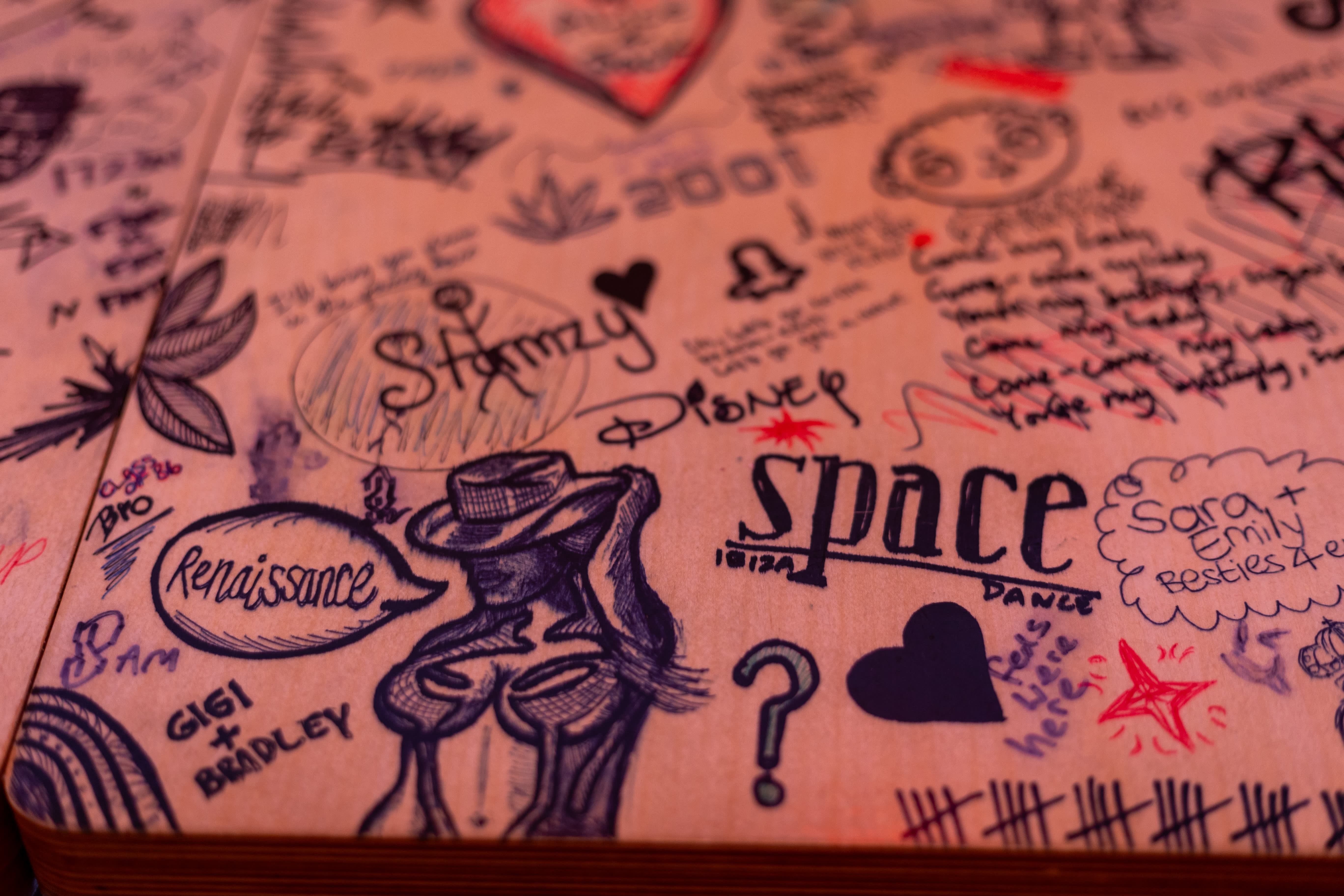 A close-up of hand-drawn Space Dance and drinks illustrations on a Simmons tabletop.