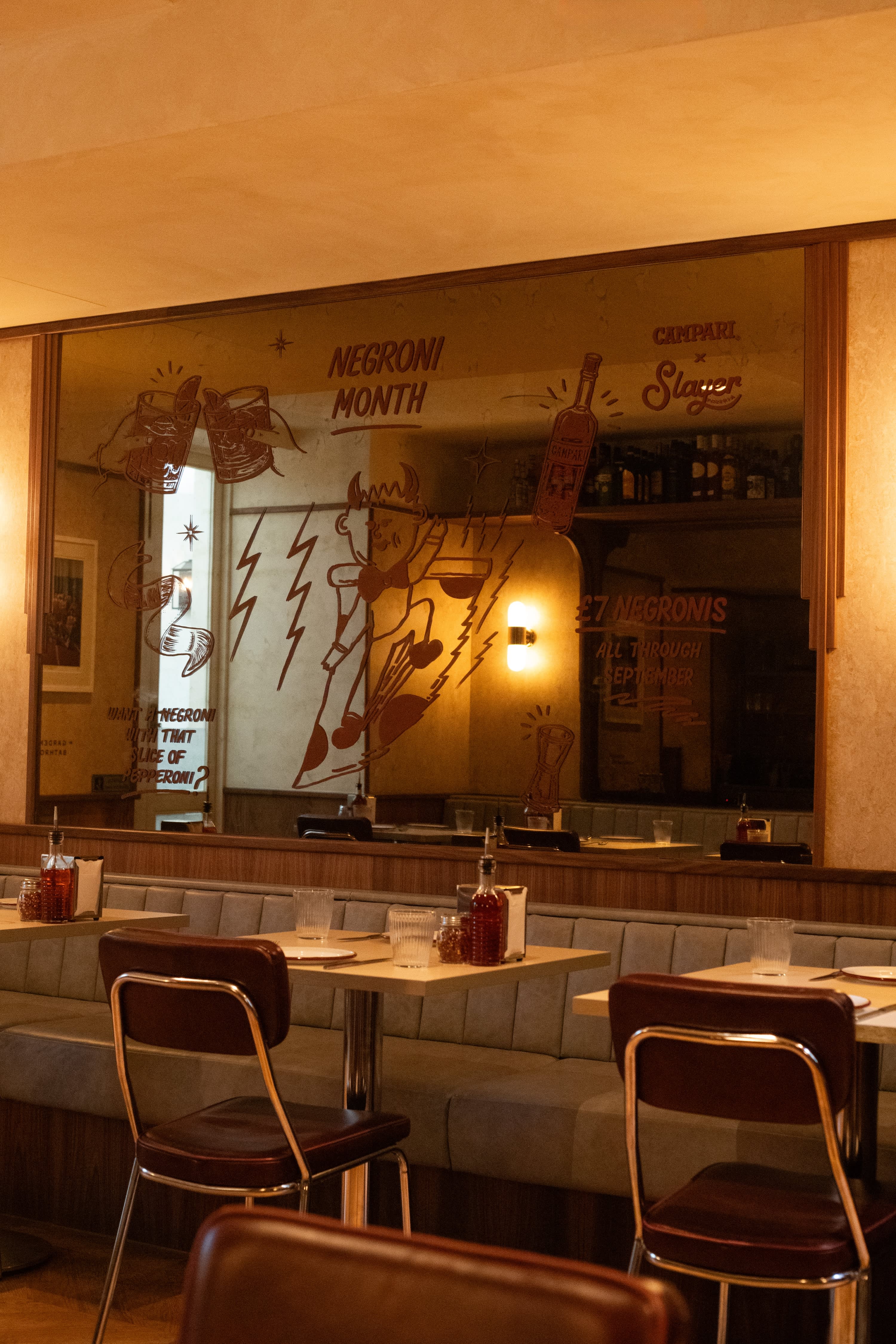 A restaurant mirror with illustrated drinks and hand-painted promotional lettering.
