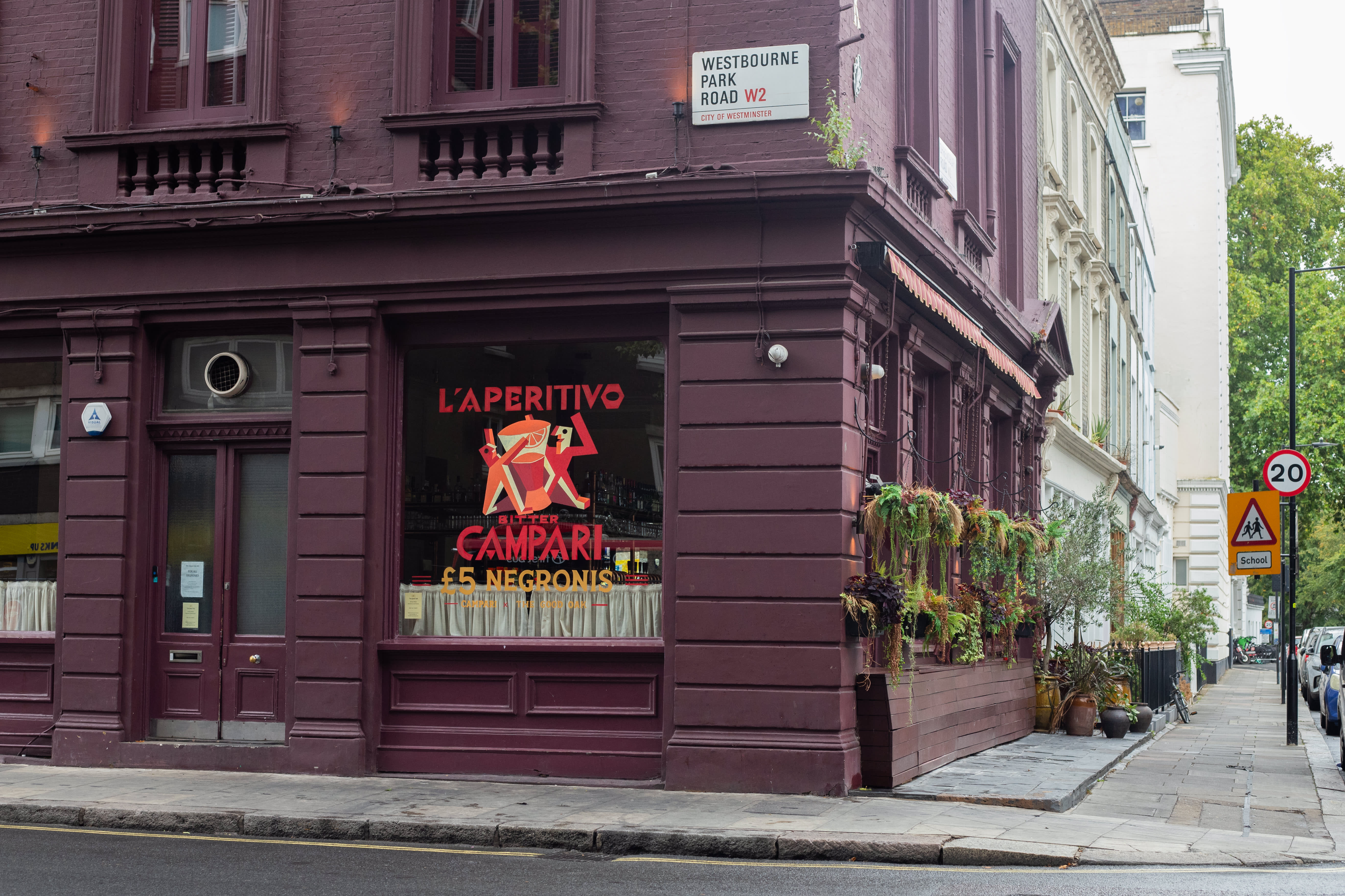 A Campari aperitivo window painting on a burgundy pub frontage.
