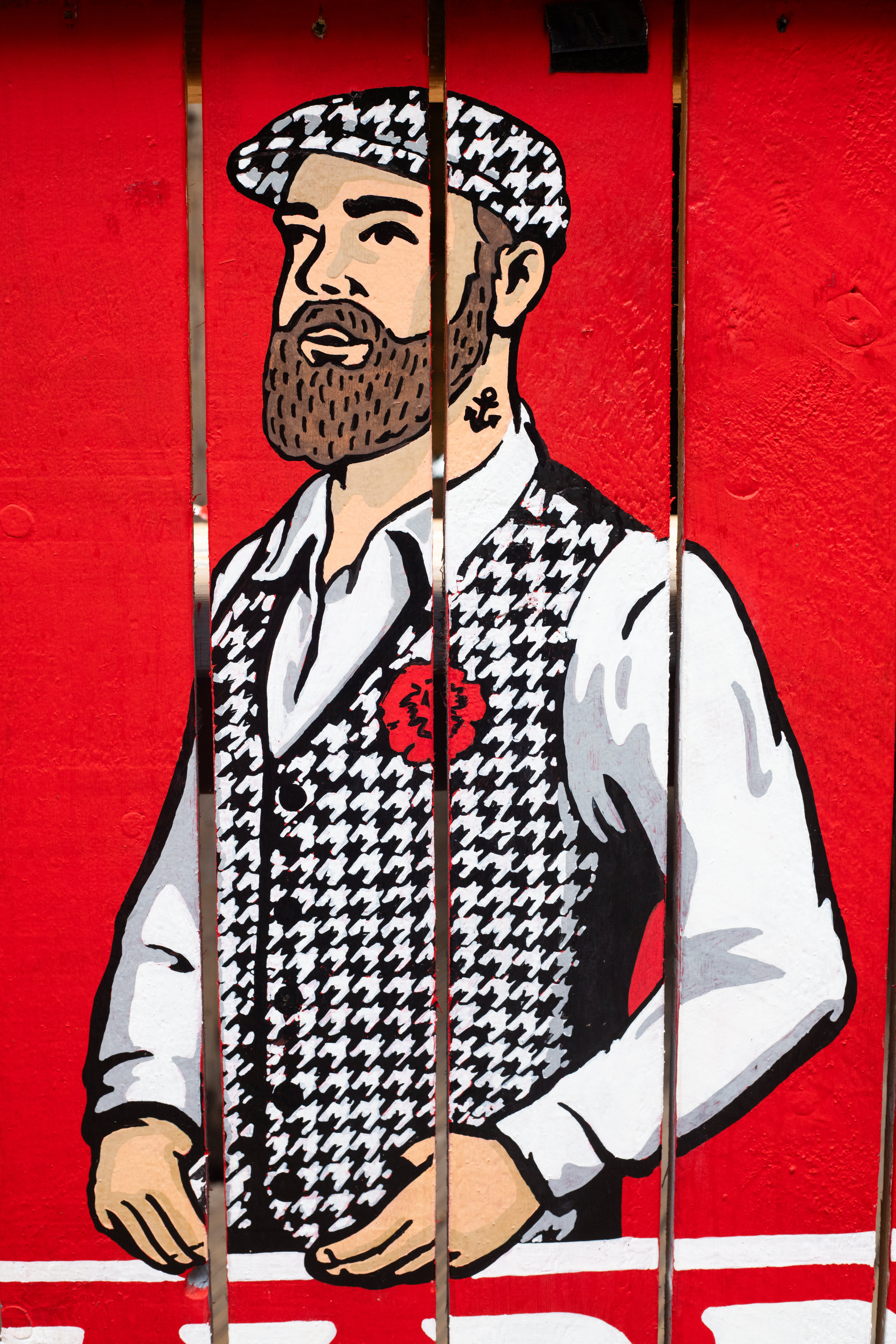 A close-up of the hand-painted Madri figure on a red timber panel.
