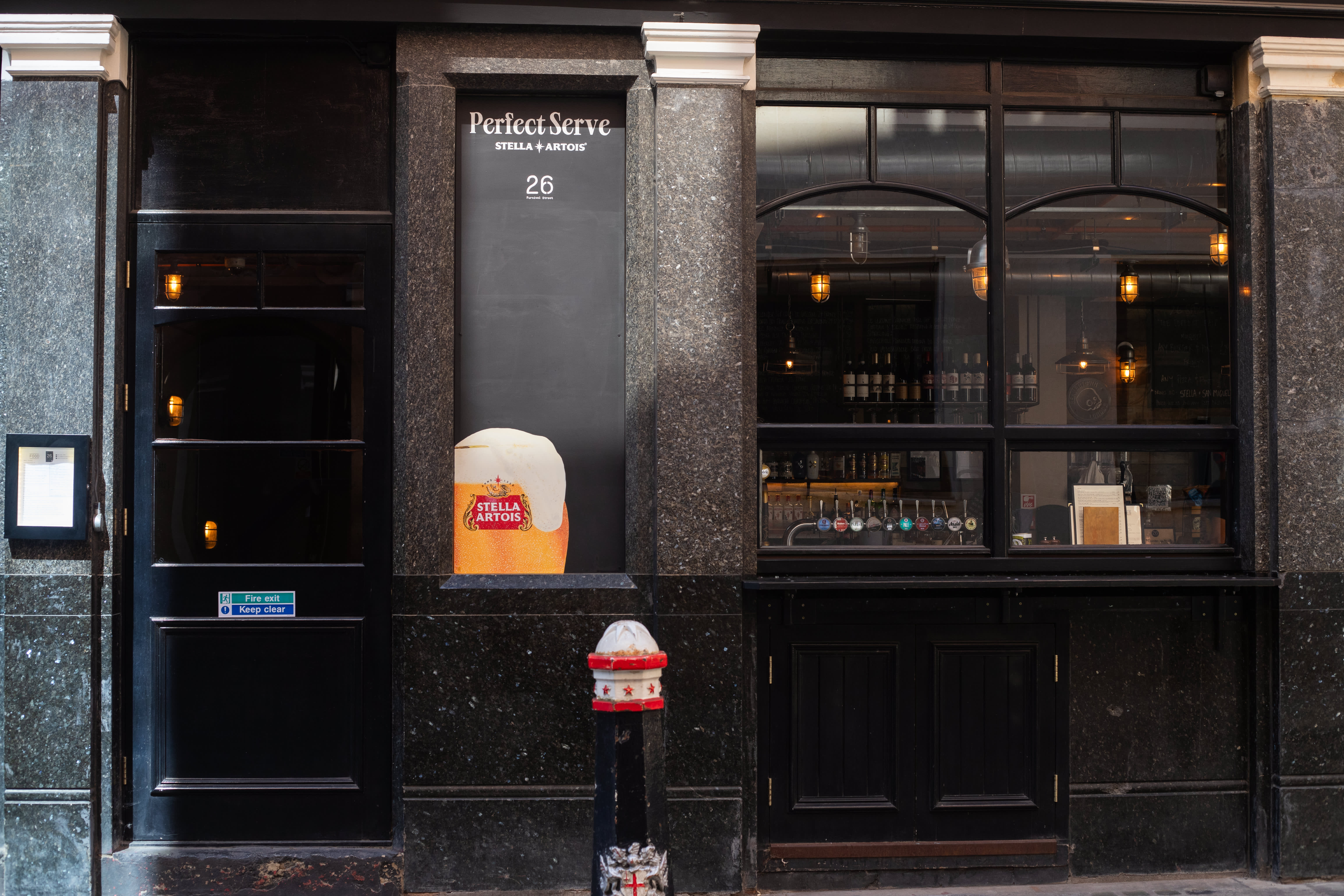 A Stella Artois window painting on a black pub frontage.