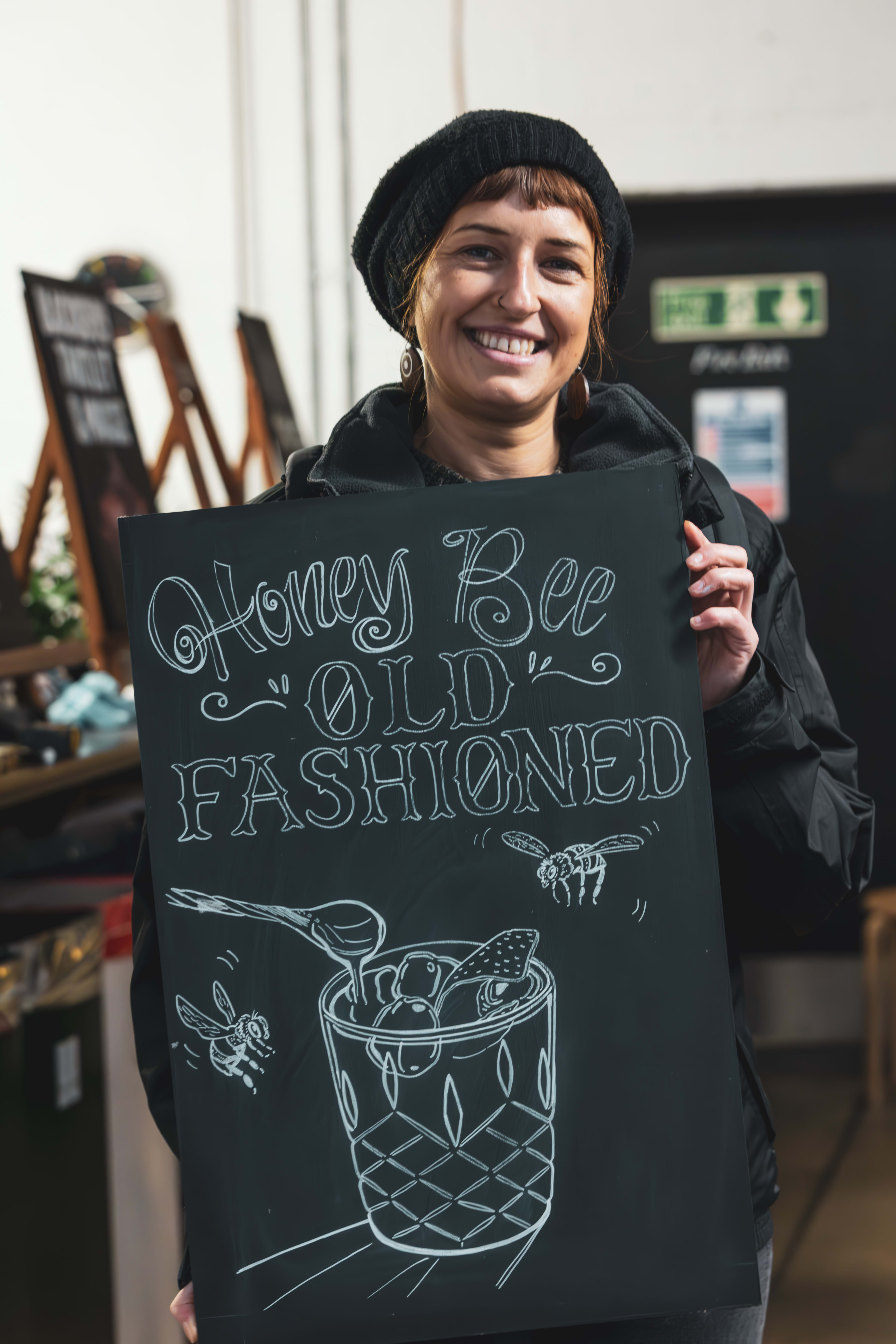 A smiling workshop participant holding her finished chalkboard artwork.