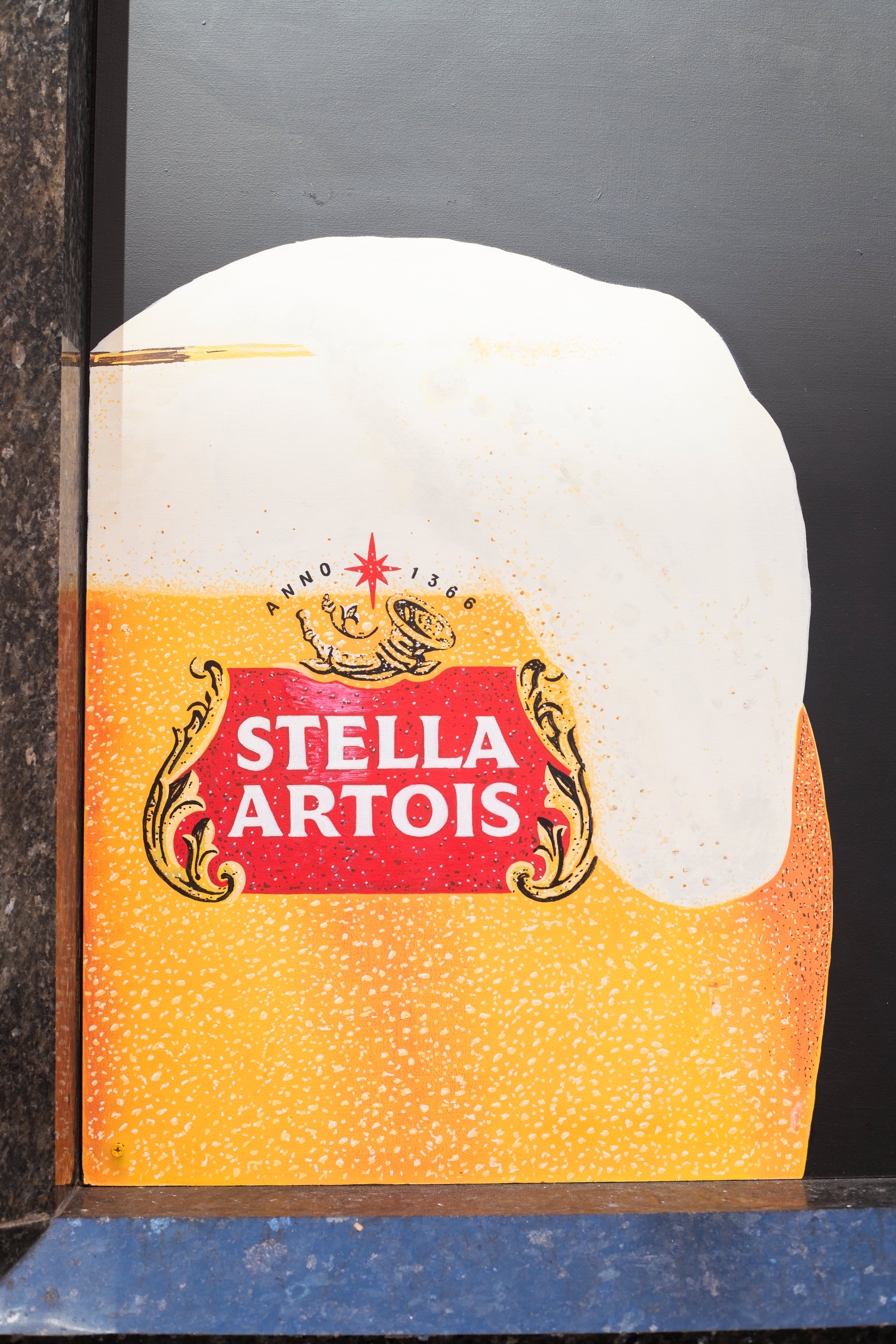 A hand-painted Stella Artois beer glass on a black pub window.