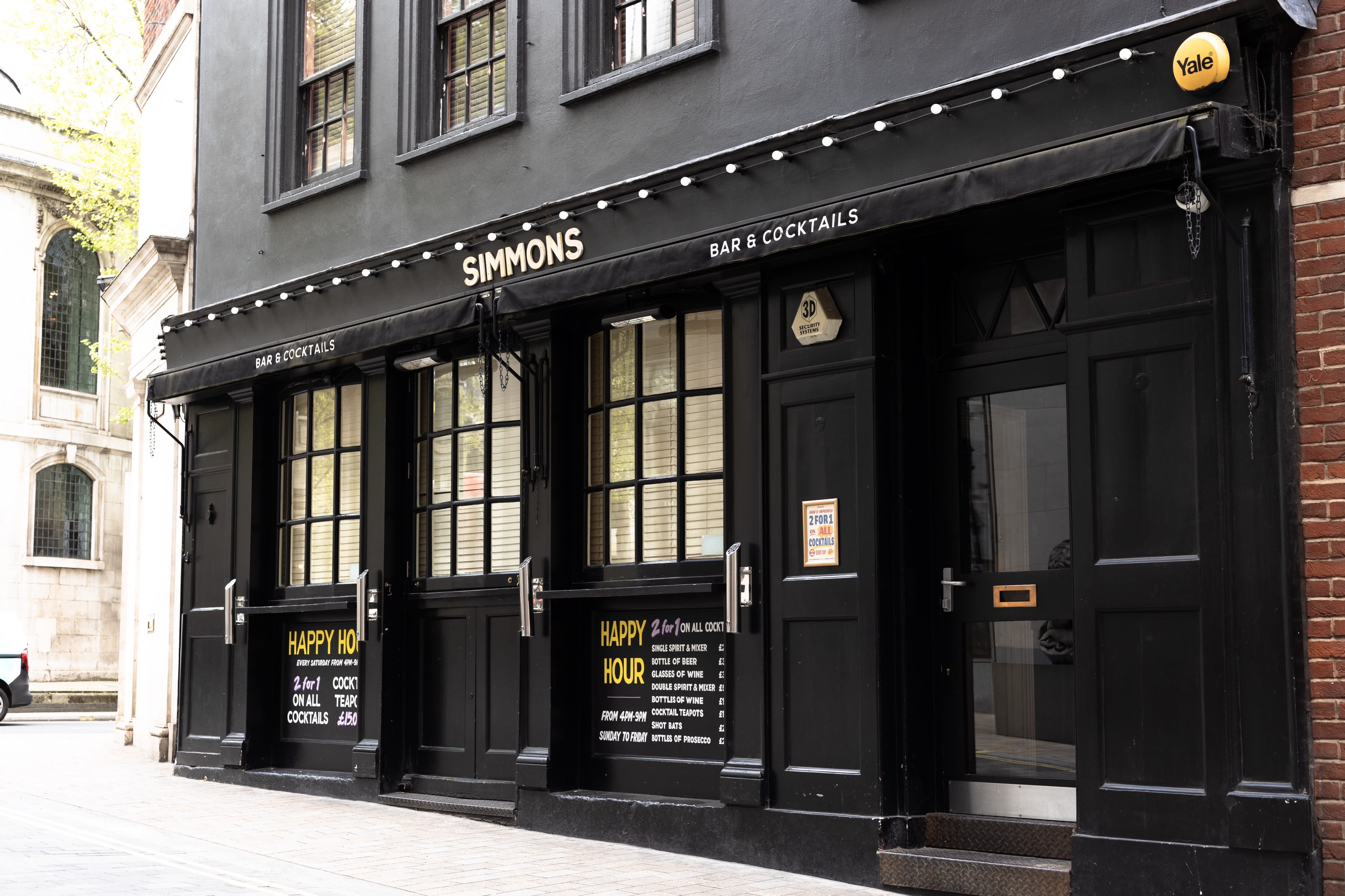 The black Simmons bar frontage with hand-painted lettering on its windows.