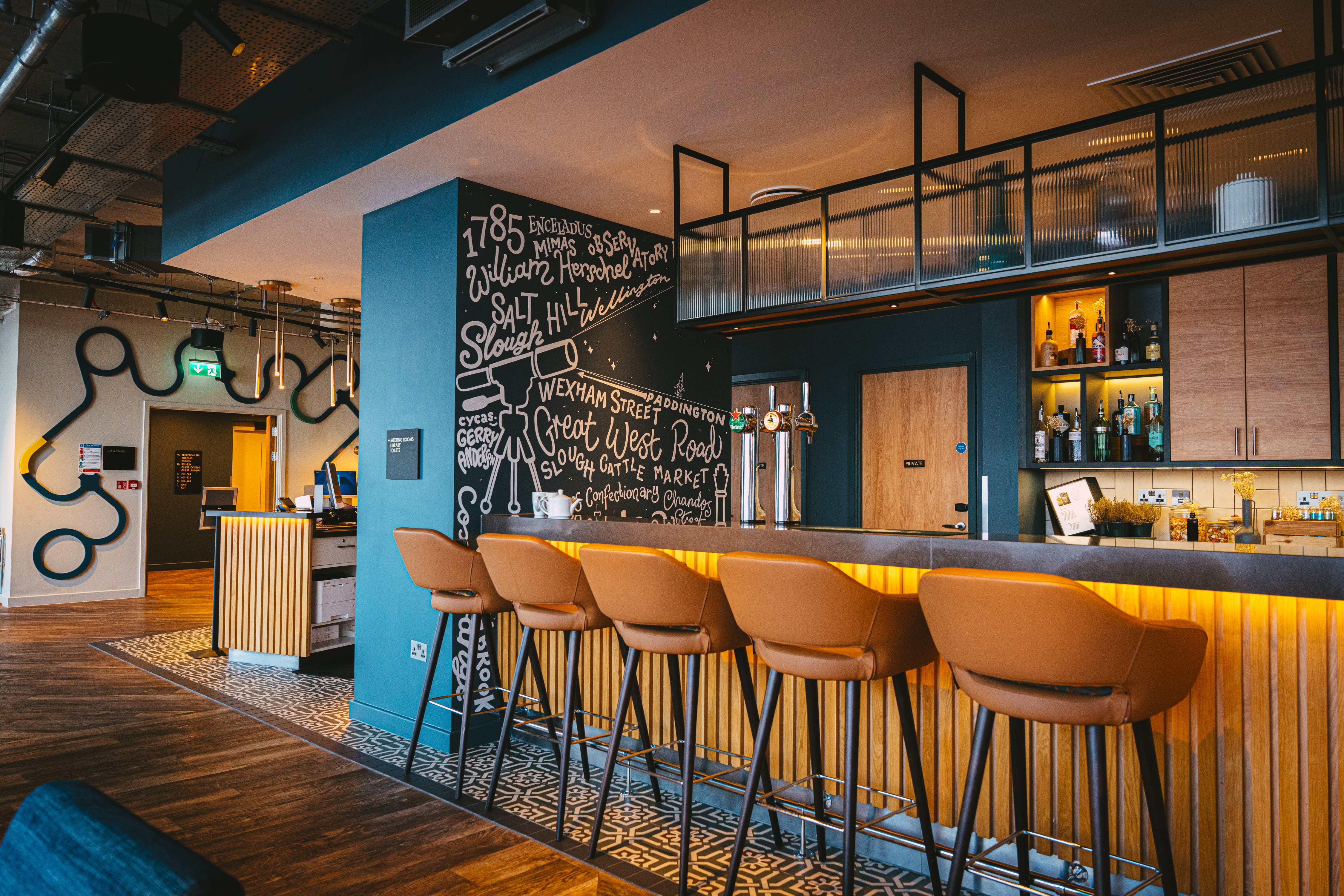 Illustrated blackboard walls and orange bar seating at Moxy.
